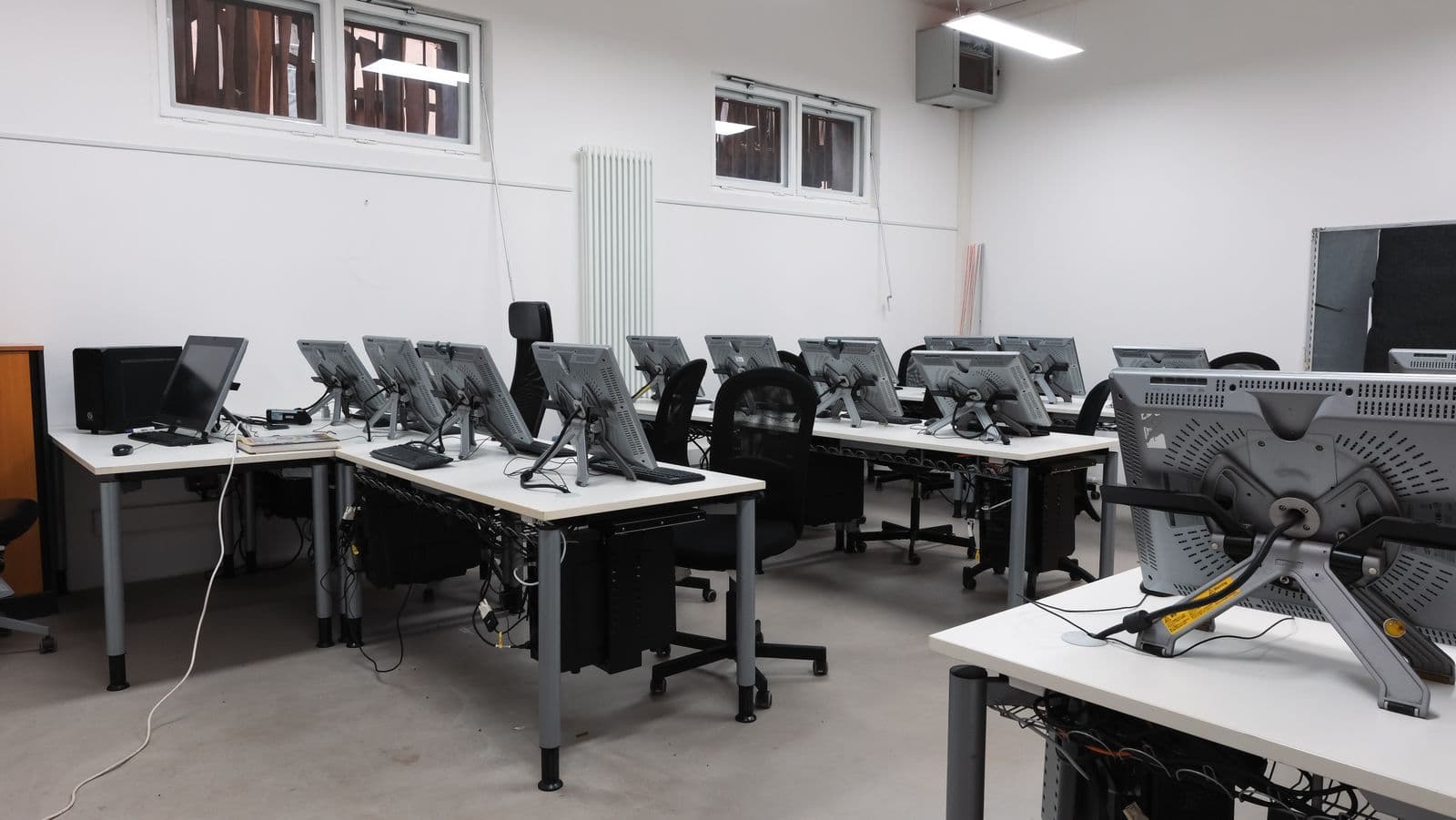 Office room of desks with computer screens and tower PCs mounted underneath